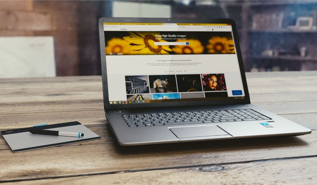 Laptop sitting on a wood surface, open to high fidelity wireframe with images, text, and a search function