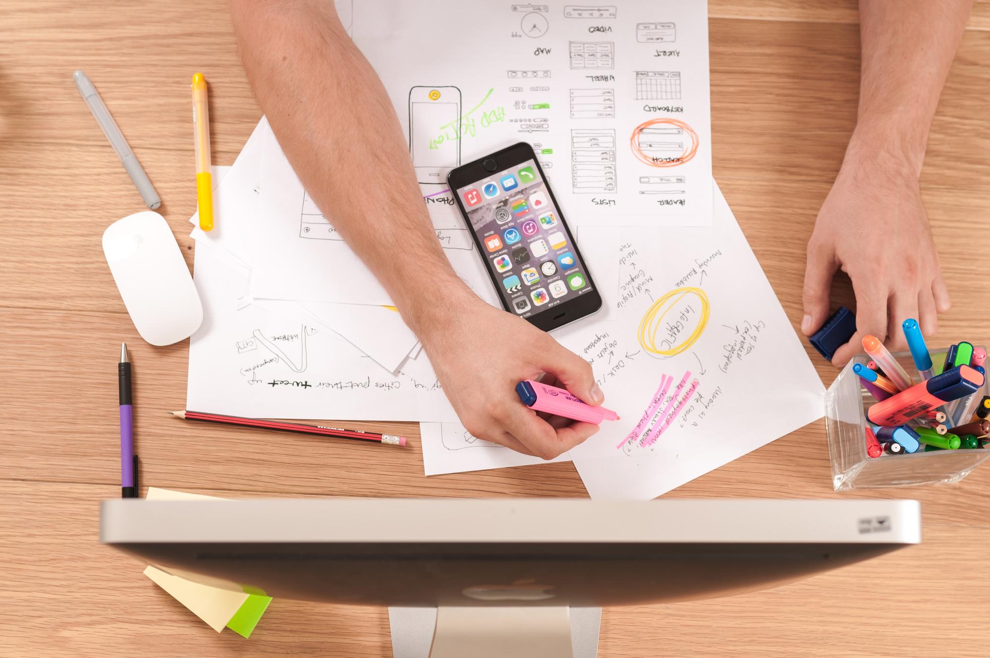 Male arm and hand holding a pink highlighter as he prioritizes an idea on a planning web.