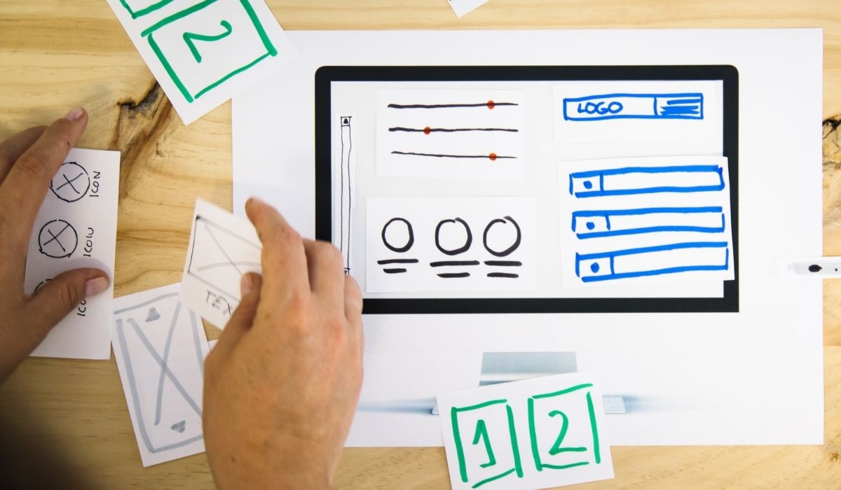 Male hands moving elements of a website around on a hand-drawn IA or wireframe website layout